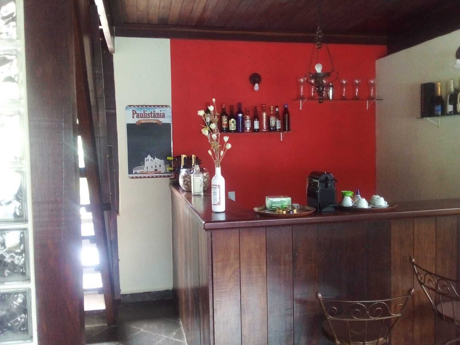 A bar area with a wooden counter, a red wall, and a poster of a building.