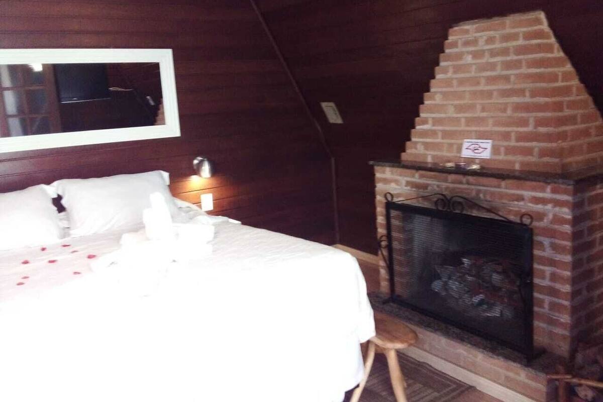 Ein Schlafzimmer mit Bett, Kamin und einem an der Wand befestigten Fernseher.