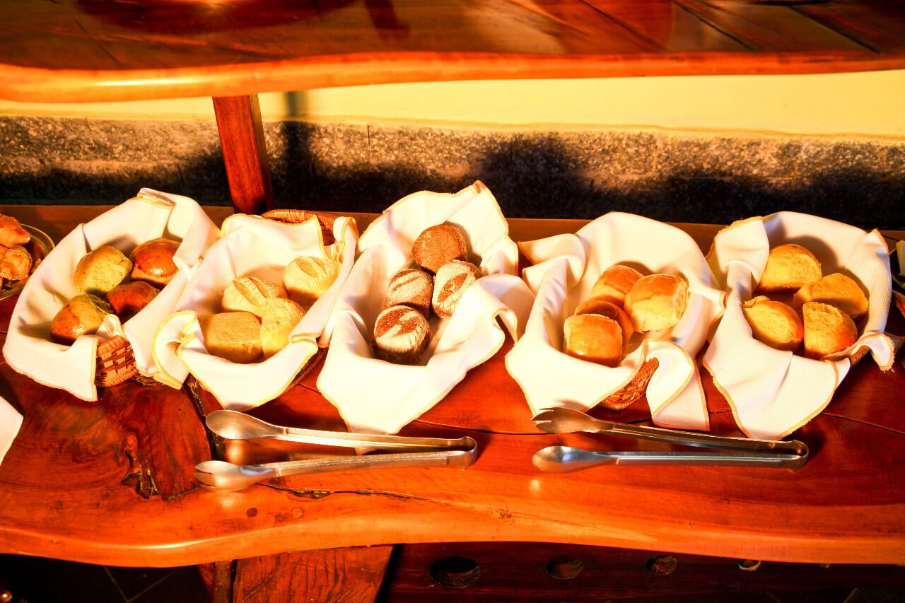 Ein Holztisch mit Körben voller verschiedener Brotsorten und Brötchen, dazu gehören Servierbesteck.