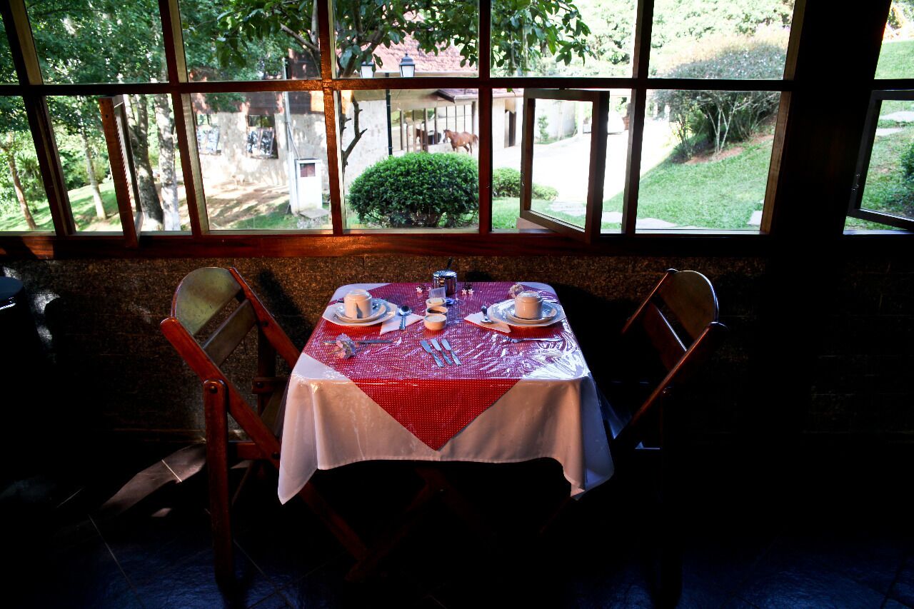 A table set for two with a red tablecloth, two plates, and a glass of water.