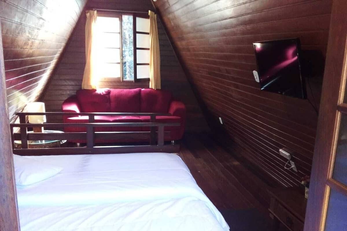 Ein Schlafzimmer mit Etagenbett, einem roten Sofa, einem Fenster mit Vorhängen und einem an der Wand befestigten Fernseher.