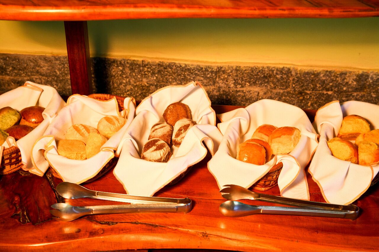 Three baskets of bread on a wooden table with spoons.