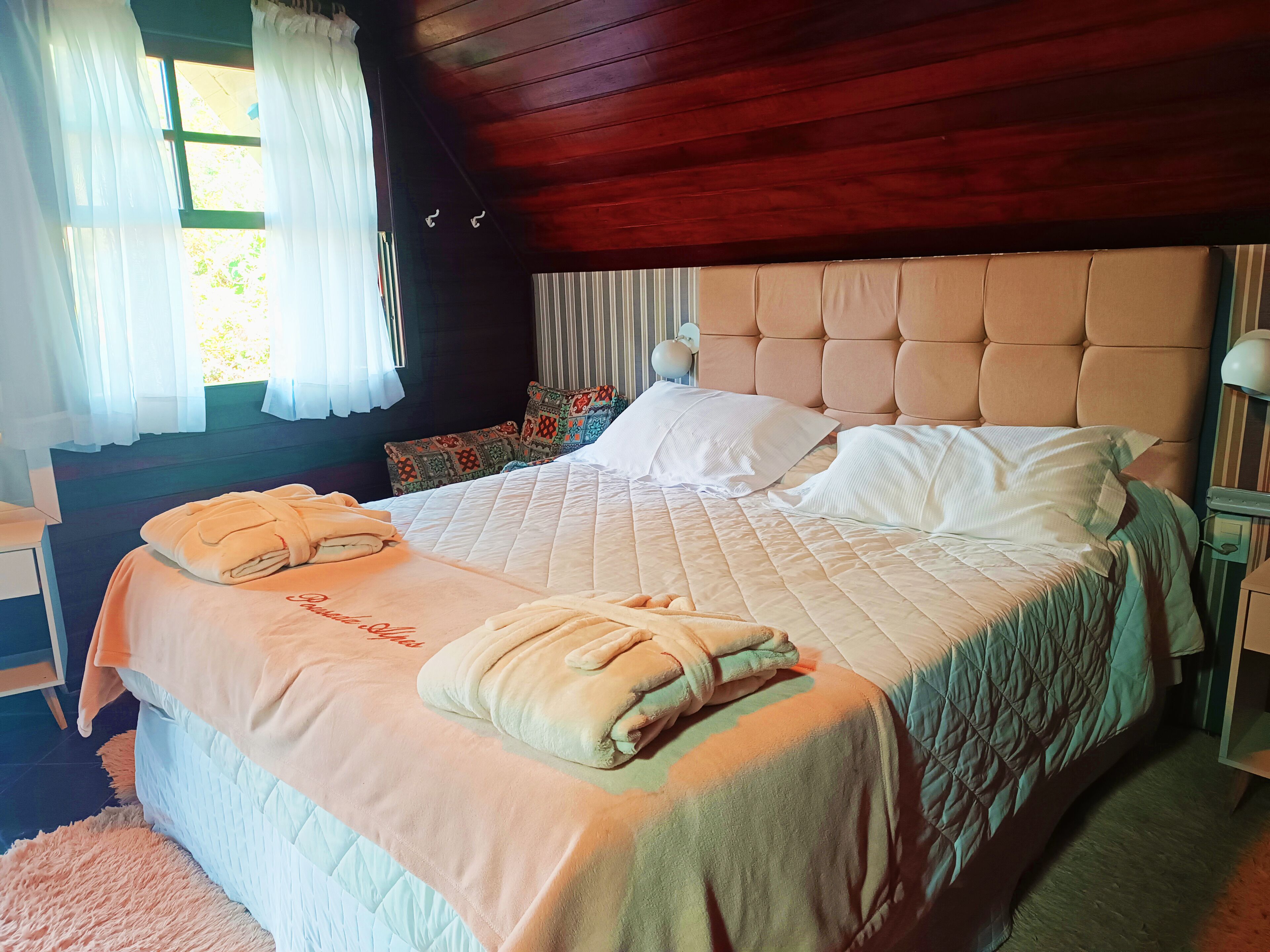 A neatly made bed with a quilted headboard, a fluffy rug, and a bedside table with a lamp.