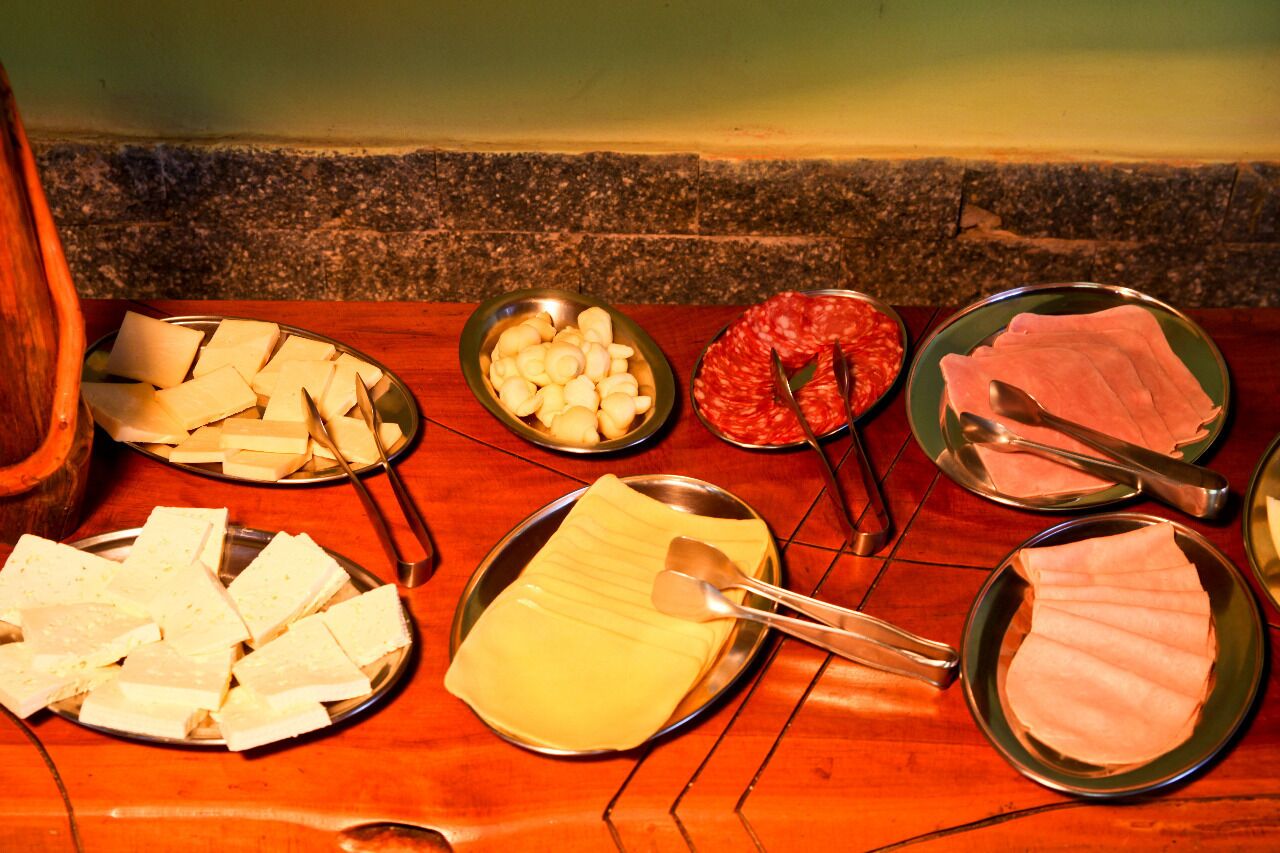 Une variété d’aliments, notamment des fromages, des charcuteries et d’autres en-cas, disposés sur une table en bois.