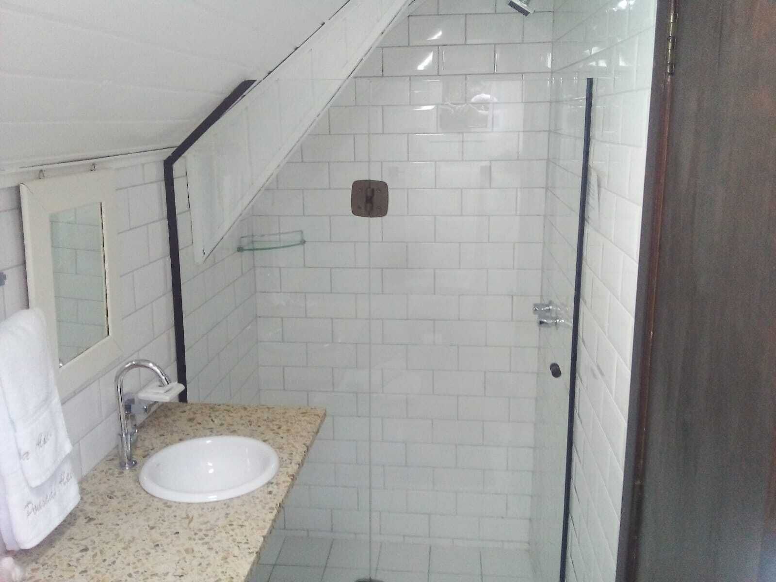A bathroom with a white sink, a glass shower enclosure, and a mirror above the sink.