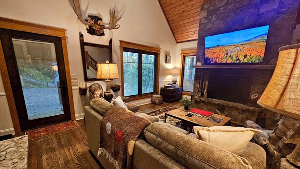 Ein gemütliches Wohnzimmer mit Kamin, Fernseher und großem Fenster.