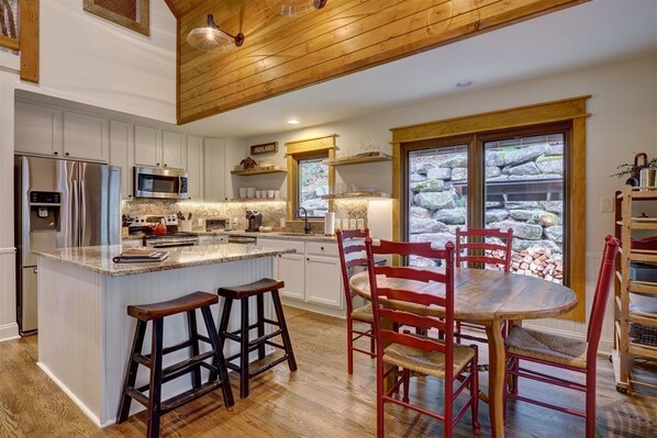 A modern kitchen with a central island, stainless steel appliances, and a stone wall view.