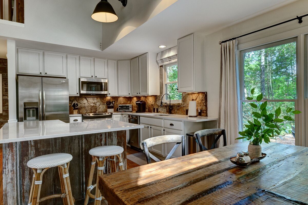 Una cocina moderna con armarios blancos, electrodomésticos de acero inoxidable y una isla grande con taburetes de bar.