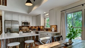 Una cocina moderna con armarios blancos, electrodomésticos de acero inoxidable y una isla grande con taburetes de bar.