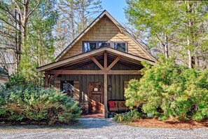 A wooden cabin with a gabled roof, a front porch, and a door with a window above it. - Heinrich - Mill Creek Cottage: Walk to Downtown | Creekside Retreat w/ Hot Tub (Highlands)