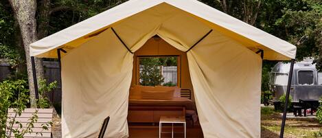 A tent with a bed, a small table, and a window.
