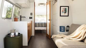 A compact RV interior with a kitchenette, a bed, and a seating area.