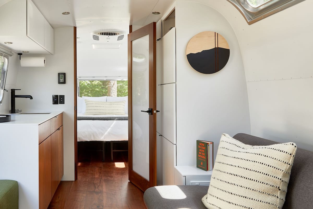 Interior de una caravana compacta, con kitchenette, un baño pequeño y una zona de descanso.