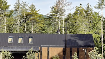 Un bâtiment moderne doté d’un toit en pente, de trois fenêtres et d’une allée gravillonnée.