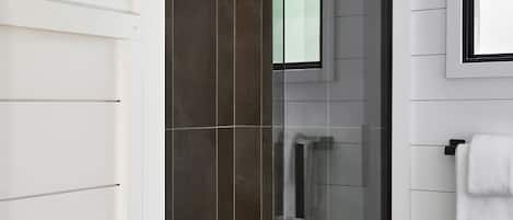 Een moderne badkamer met een douchecabine van glas, witte wanden en een betegelde vloer.