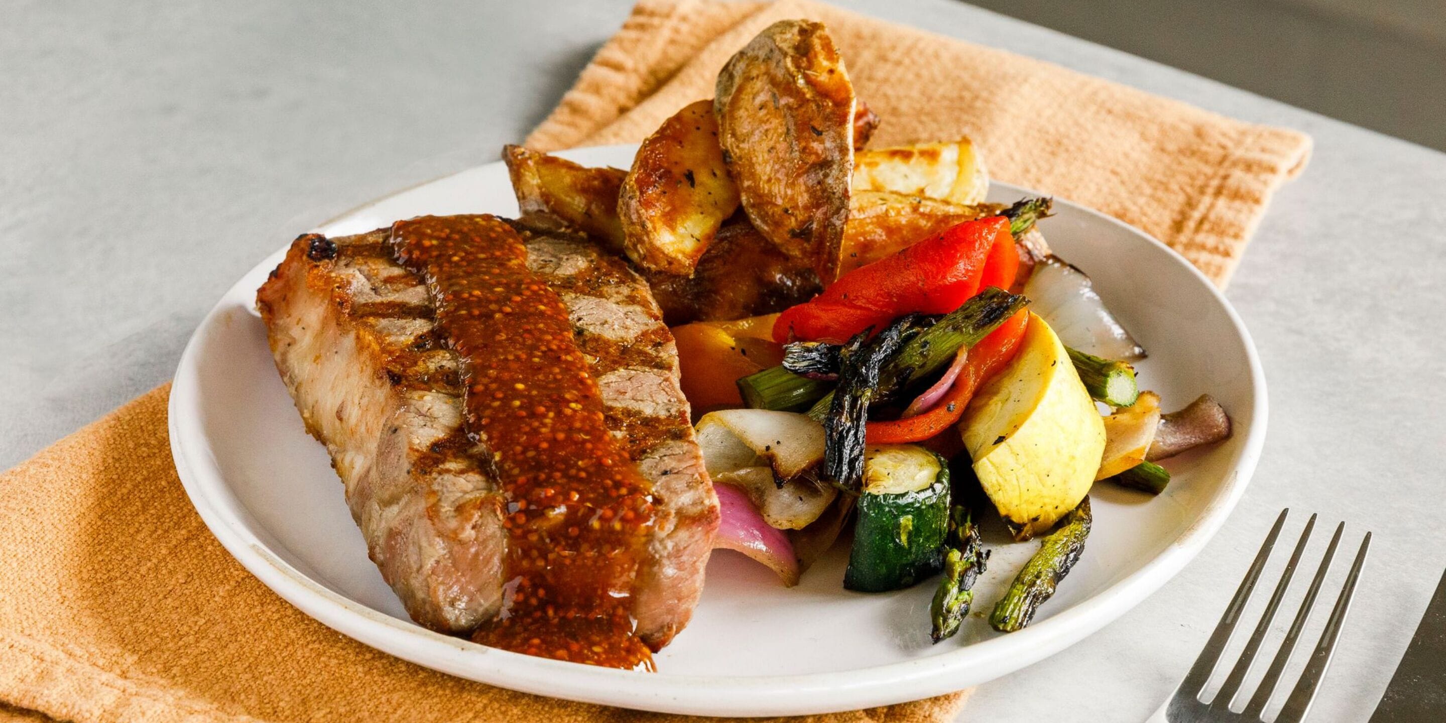 A plate of roasted meat with vegetables and a side of bread.