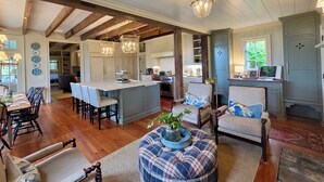 Un vaste espace de vie doté d’un plancher en bois, d’une table à manger et d’une cuisine située à l’arrière-plan.