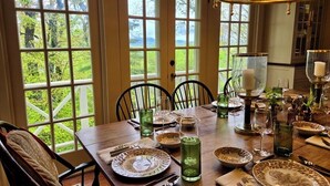 Une table à manger dressée avec des assiettes, des verres et des couverts, entourée de chaises.