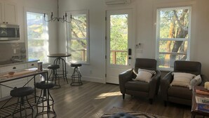 Una sala de estar moderna con zona de cocina, que incluye una mesa de comedor, taburetes de bar y una chimenea.