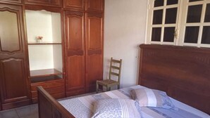 A bedroom with a wooden bed, a chair, and a wardrobe with shelves. - 5 Bedroom Villa in Le Lamentin (Le Lamentin)