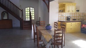 A dining area with a table set for four, wooden chairs, a blue vase, and a staircase leading to another room. - 5 Bedroom Villa in Le Lamentin (Le Lamentin)