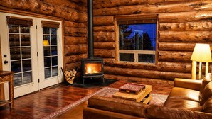 A log cabin interior with a fireplace, leather sofa, and a rug. - Custom log cabin tucked away in private forest (Hartsel)