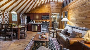 A cozy interior with a wooden dining table, a sofa, and a kitchen area with modern appliances.