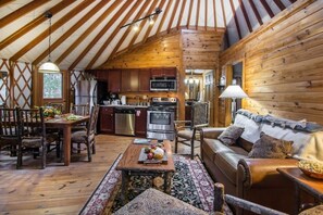 A cozy interior with a wooden dining table, a sofa, and a kitchen area with modern appliances.