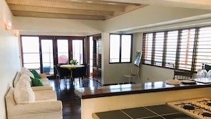 A hotel room with a dining area, a sofa, a table with chairs, and a view through the windows. - Top Seaview Apartment with pool (Scarborough)