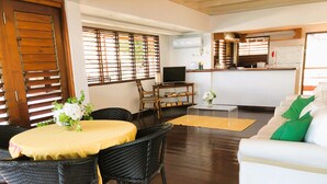 A living room with a dining area, a sofa, a TV, and a kitchen area. - Top Seaview Apartment with pool (Scarborough)