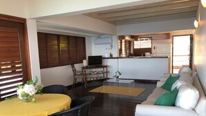 A living room with a sofa, a dining table with chairs, a coffee table, and a TV on a stand. - Top Seaview Apartment with pool (Scarborough)