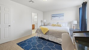Une chambre d’hôtel avec un lit, un bureau, une chaise, une lampe et un tableau au mur.