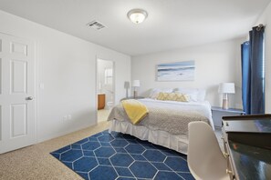 A hotel room with a bed, a desk, a chair, a lamp, and a painting on the wall. - The Las  Alturas  House (Alamogordo)