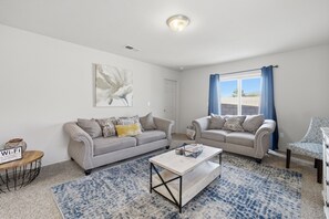 Ein Wohnzimmer mit zwei Sofas, einem Couchtisch, einem Teppich und einem Gemälde an der Wand.