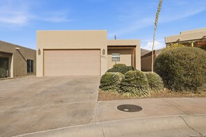A modern house with a beige garage door, a mailbox, and a well-maintained front yard with cacti and shrubs.
