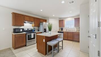 A modern kitchen with wooden cabinets, stainless steel appliances, and a central island with seating.