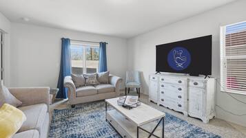 A living room with a sofa, a coffee table, a TV, and a patterned rug.
