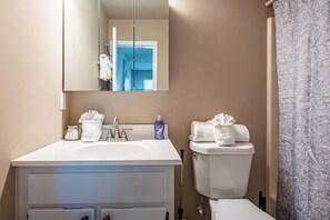 Ein Badezimmer mit weißem Waschbecken, Spiegel, Toilette und Duschvorhang.