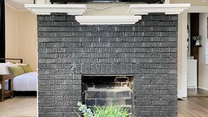 Una sala de estar moderna con chimenea de piedra, un televisor de pantalla plana montado encima y una planta en maceta al frente.