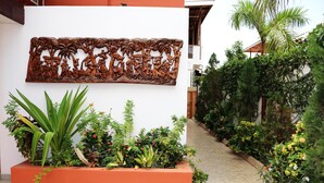 A courtyard with a decorative wall, a planter with various plants, and a pathway.
