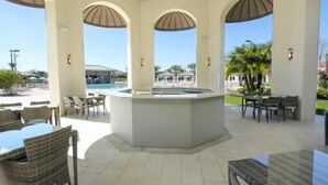 A covered outdoor area with a pool, seating, and a central bar.