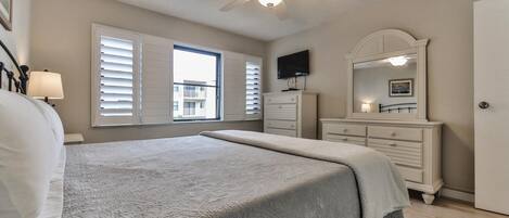 A bedroom with a bed, a dresser, a television, and a ceiling fan.