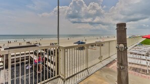 A beach view with a metal railing, a concrete pillar, and a clear sky.