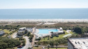 An aerial view of a resort with a large swimming pool, beach access, and a road leading to the property. - Admiral’s Row 203: Romantic Oceanfront Retreat with Bunk Beds (Hilton Head Island)