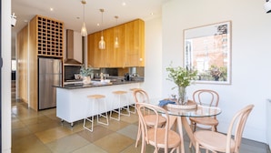 Een moderne keuken met houten kastjes, een roestvrijstalen koelkast en een centraal eiland met barstoelen.