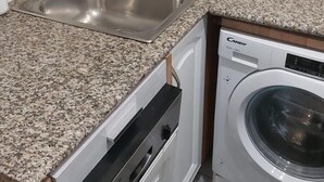 Une cuisine dotée de plans de travail en granit, d’un évier en acier inoxydable, d’un lave-vaisselle et d’une machine à laver.