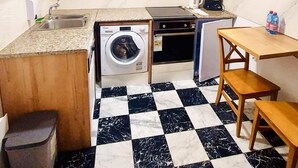 Une cuisine compacte équipée d’un lave-linge, d’un petit four et d’une machine à café.