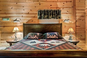 A cozy wooden cabin bedroom with a bed, two nightstands, and a window with curtains.
