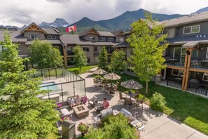 Ein Hotelinnenhof mit Sitzgelegenheiten im Freien, einem Pool und Blick auf die Berge.