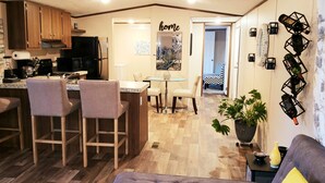 Eine kompakte Küche mit Holzschränken, einem schwarzen Kühlschrank und einem Essbereich mit einem kleinen Tisch und Stühlen.